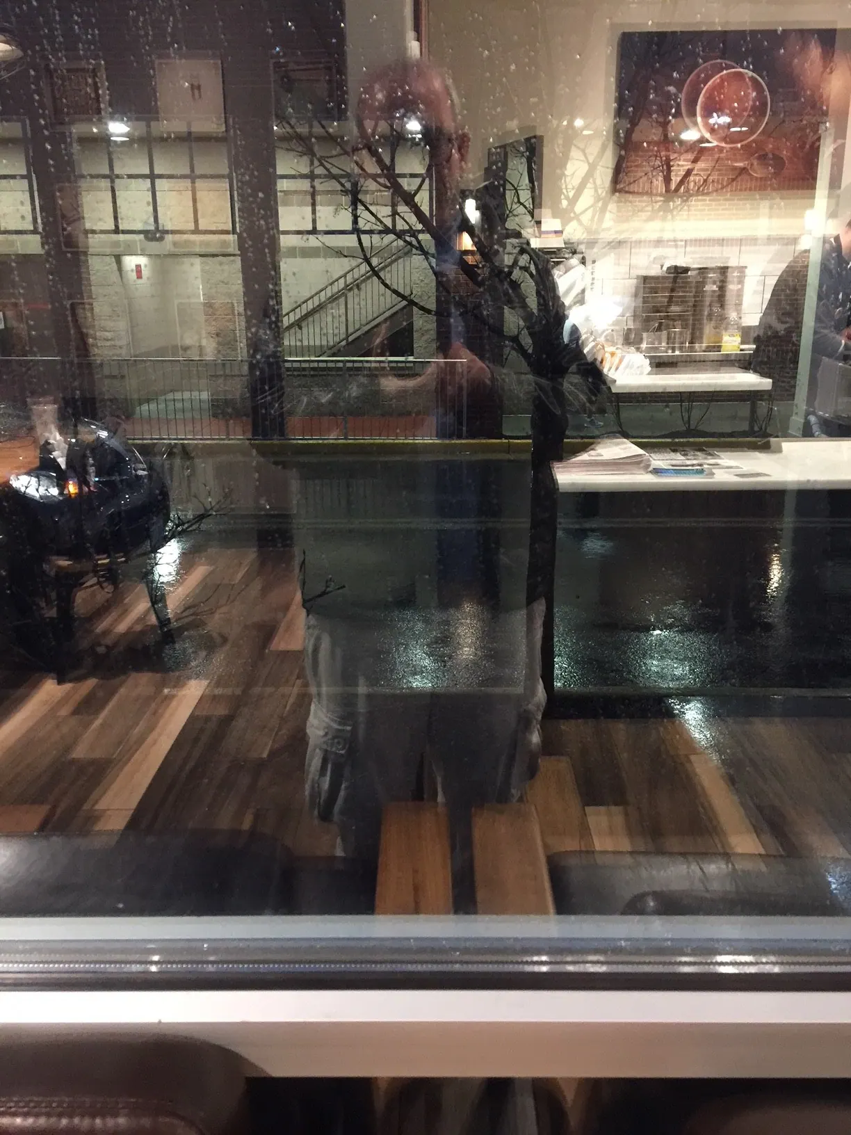 बारिश में काँच वाली खिड़की के पास हैदराबाद के कैफ़े का दृश्य